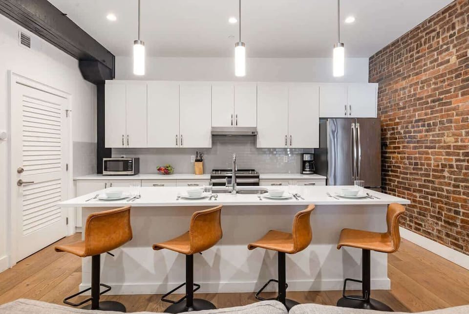 The kitchen features stainless steel appliances, a large island, and breakfast bar seating for four—ideal for casual dining.