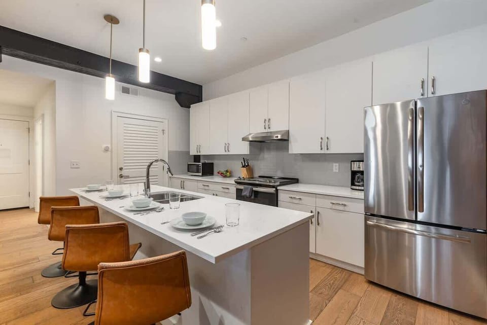 The kitchen features stainless steel appliances, a large island, and breakfast bar seating for four—ideal for casual dining.