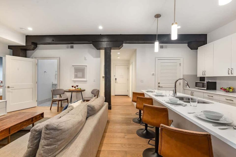The living room features an open-concept design with a charming brick wall, cozy seating, and a Smart TV for relaxing nights in.