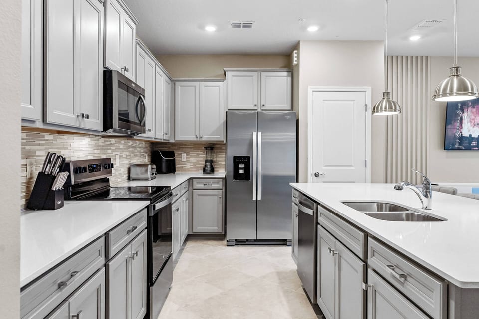 Enjoy culinary delights in this stylish kitchen, equipped with stainless steel appliances and elegant gray cabinetry. The light countertops and warm tile backsplash create a sophisticated environment for your cooking experience.