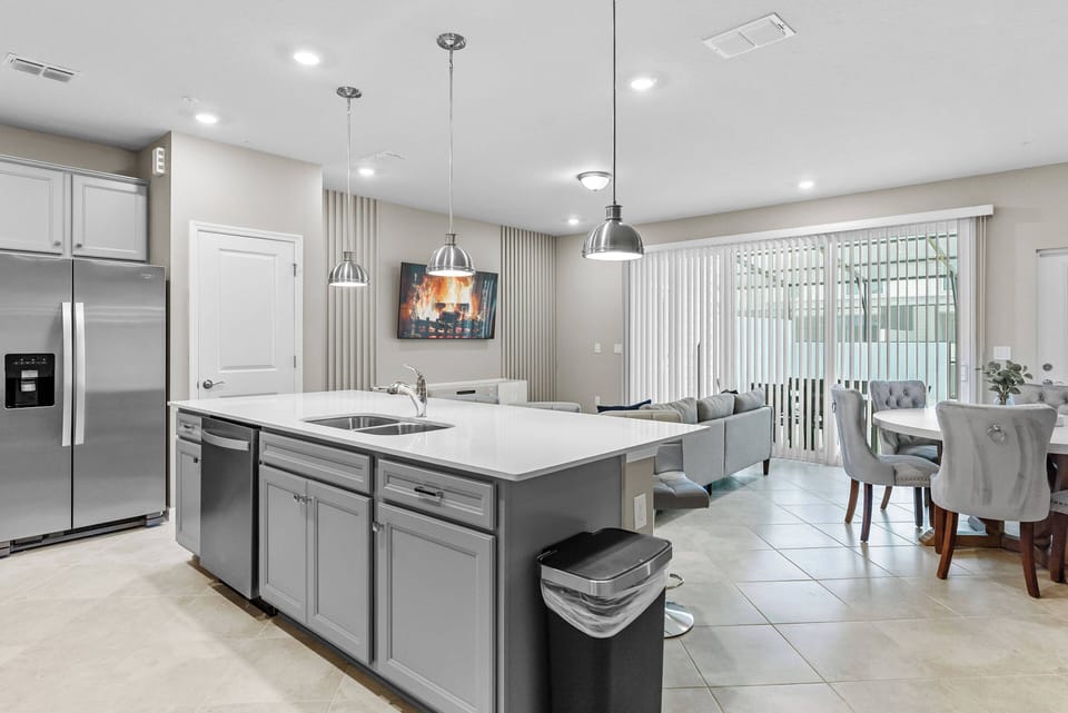 Discover a beautifully designed kitchen with sleek gray cabinetry and a spacious island ideal for gatherings. Enjoy abundant natural light through sliding glass doors, brightening the stylish dining area with cozy seating.