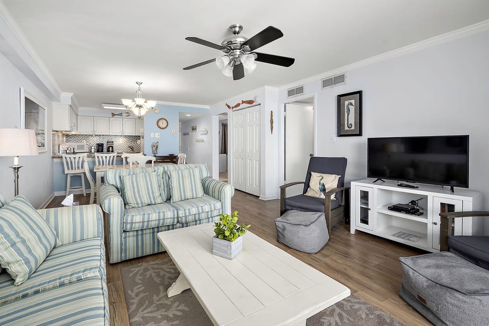Cozy coastal living room with smart TV, dining table and fully stocked kitchen