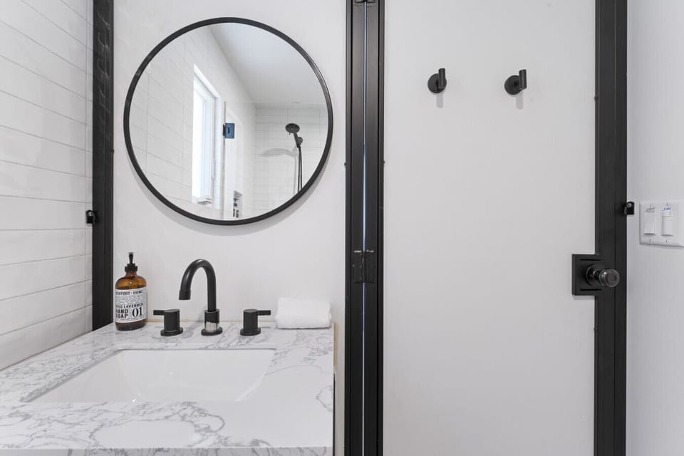 Modern vanity w/ round mirror, sleek fixtures & crisp white details