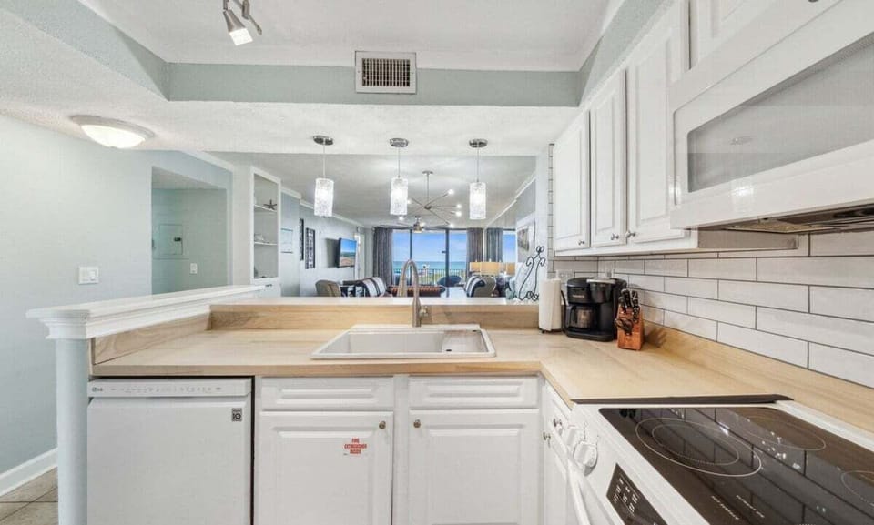 This stylish kitchen features white cabinetry, modern appliances, and an open layout perfect for beachfront meal prep.