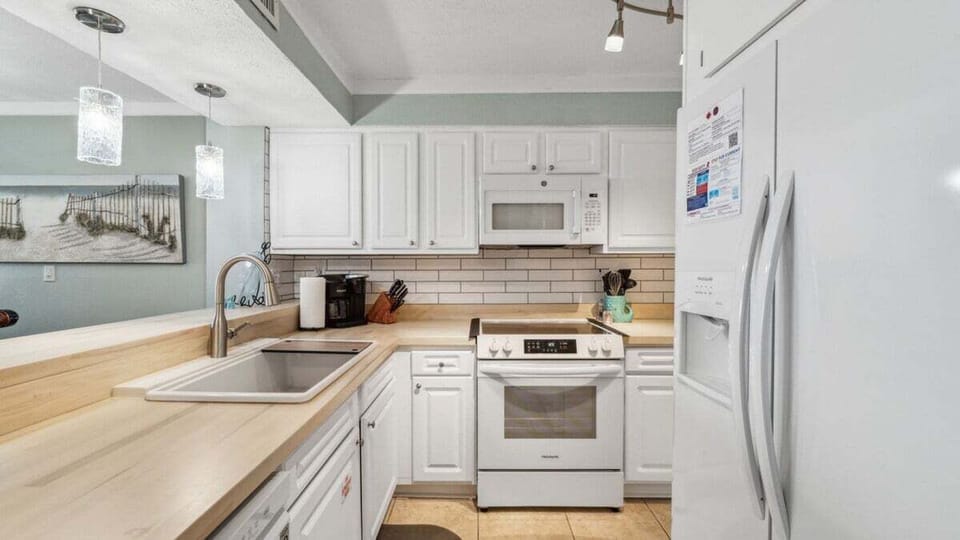 This bright kitchen boasts white cabinetry, modern appliances, subway tile backsplash, and light wood countertops—perfect for home cooking.