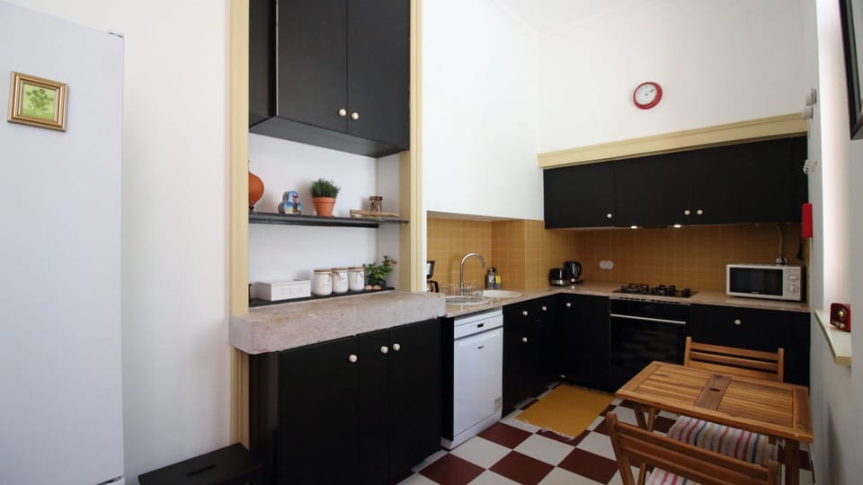Cook like a local in this vintage-modern kitchen with checkerboard floors, sleek black cabinetry, and all the essentials to prepare a hearty Portuguese meal. #Kitchen #FullyEquipped #HolidayRental