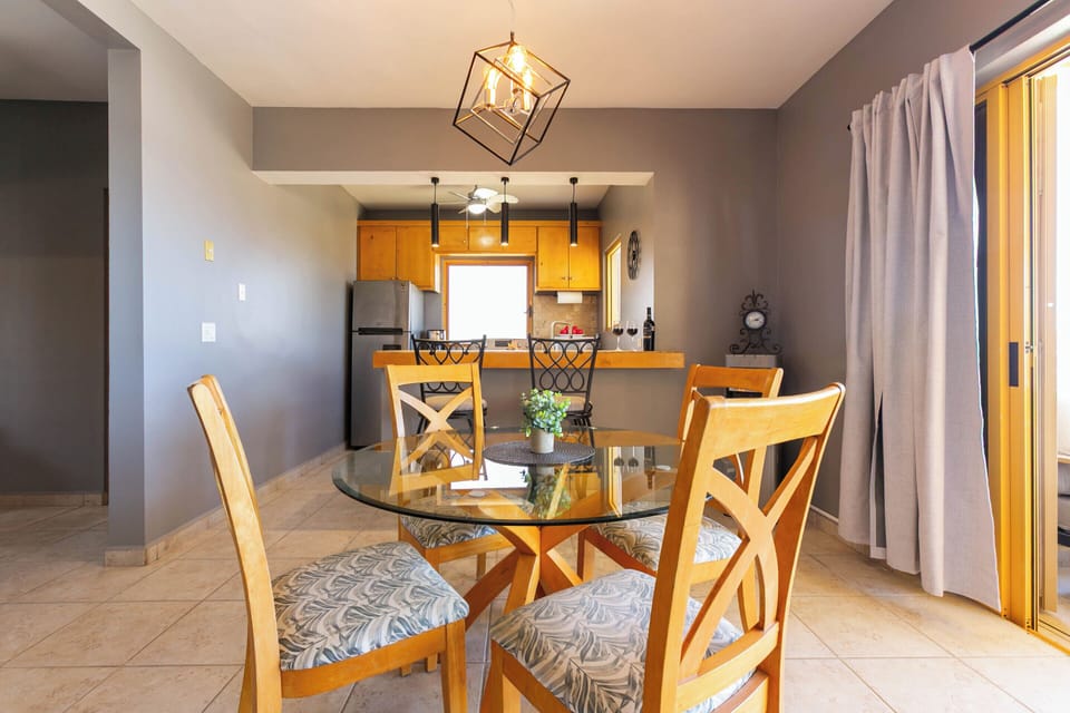Open-concept living space with a dining table that seats 4, flowing into a spacious patio with spectacular views
