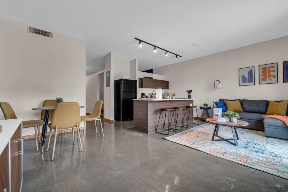 Spacious open-concept living and dining area featuring a vibrant blue sofa, modern furnishings, and a stylish entertainment setup—ideal for gatherings and relaxation.