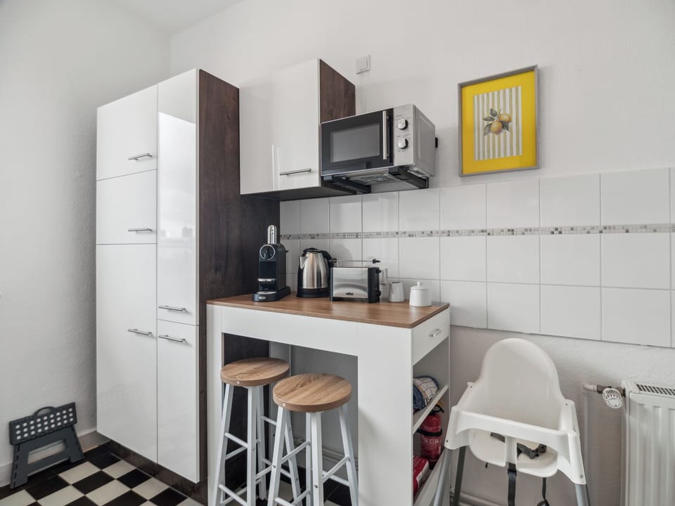 Eine kompakte Frühstücksecke mit Barhockern, Kaffeemaschine und Wasserkocher bietet den idealen Platz für den Start in den Tag.