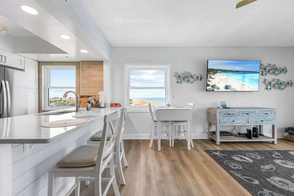 Bright kitchen and dining area with ocean views and coastal decor.