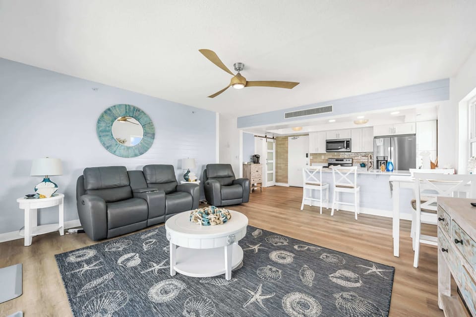 Open-concept living area with leather recliners and a modern kitchen bar.