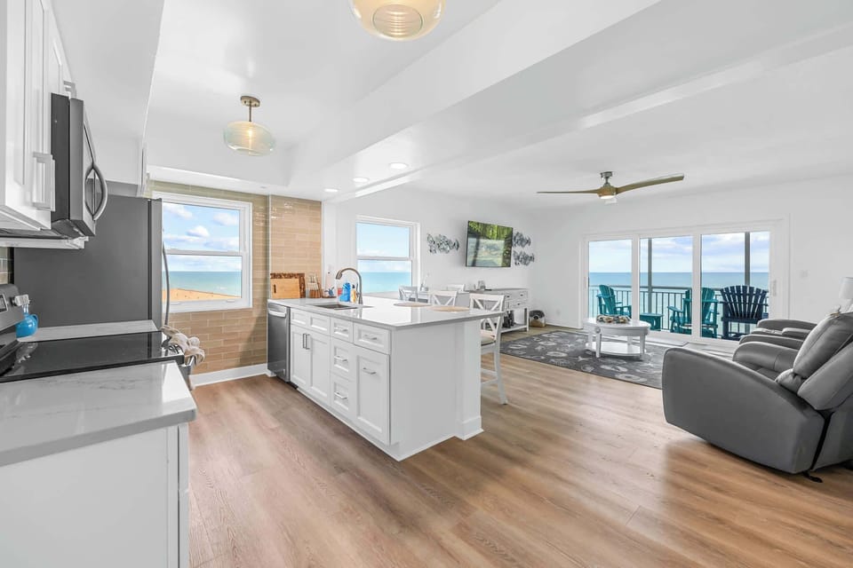 Bright open kitchen and living area with ocean views and modern finishes.