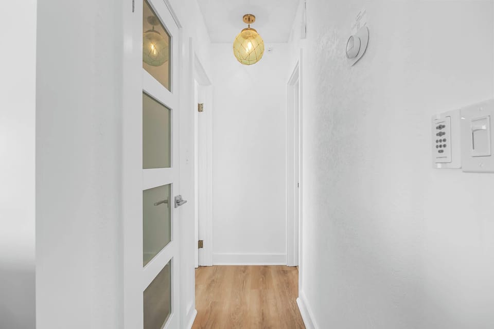 hallway with wood flooring and a modern pendant light