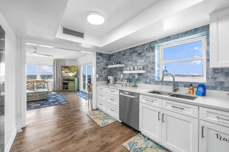 Modern kitchen with blue tile backsplash and a view into the living area with natural light
