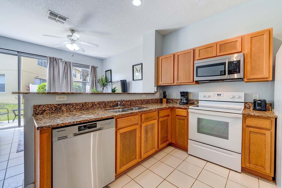 Modern kitchen with granite countertops and stainless steel appliances overlooking the living area.