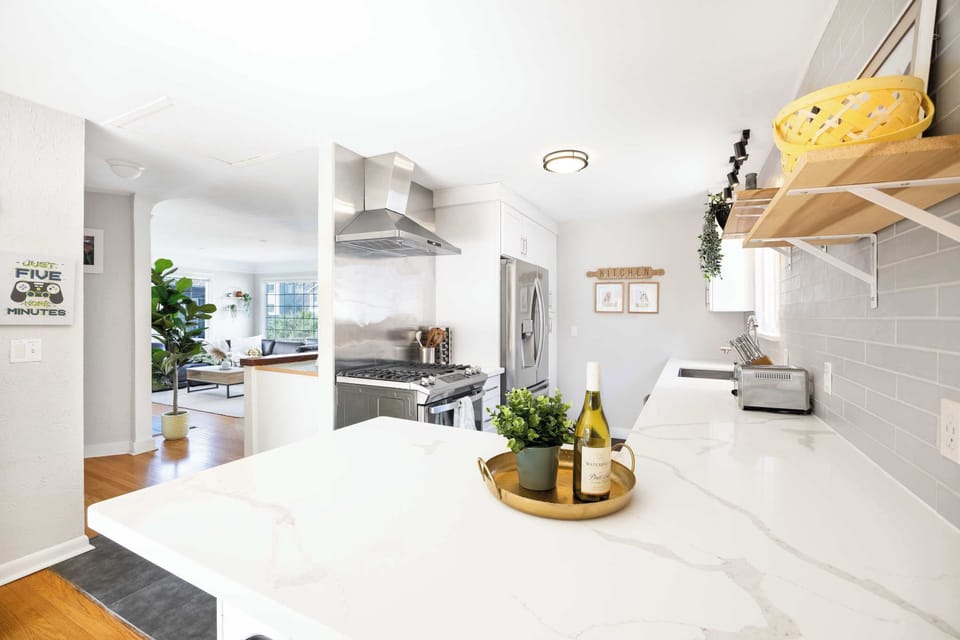 A potted plant on the marble island, framed by wooden shelves and a stainless hood—equally ready for cooking or casual happy hours.