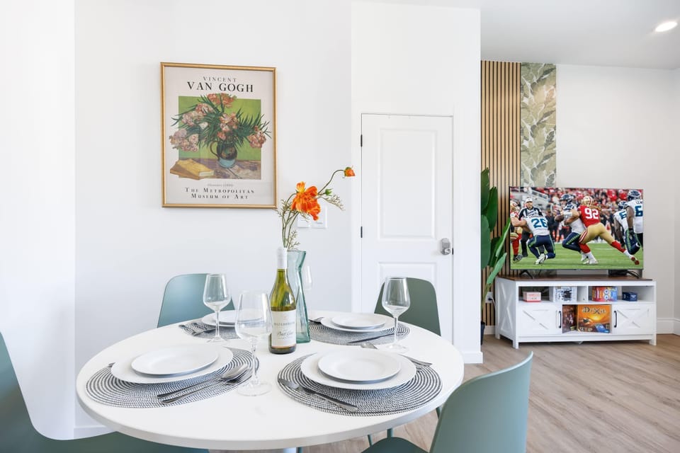 Enjoy meals in the dining space with a round sleek table , chic green chairs,and tableware ready for a gathering.