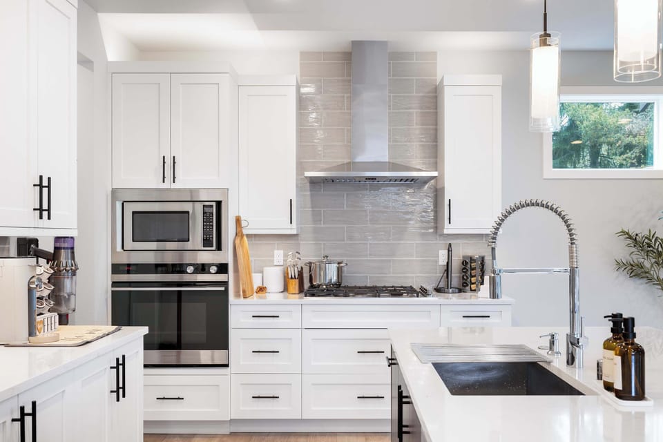 The kitchen boasts bright cabinetry, marble countertops, and a large island for meal preparation or casual dining.