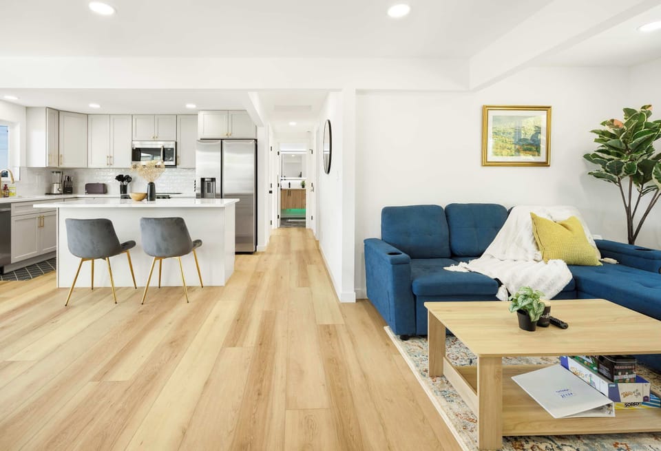 The open layout connects the living area to the kitchen, creating an inviting space for socializing. The modern aesthetic, warm wood flooring, and thoughtful decor make this home feel cozy and elegant.