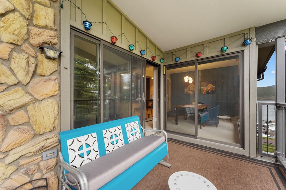 Step onto your private balcony and unwind on this cheerful blue seating while colorful string lights create magical ambiance for evening relaxation.