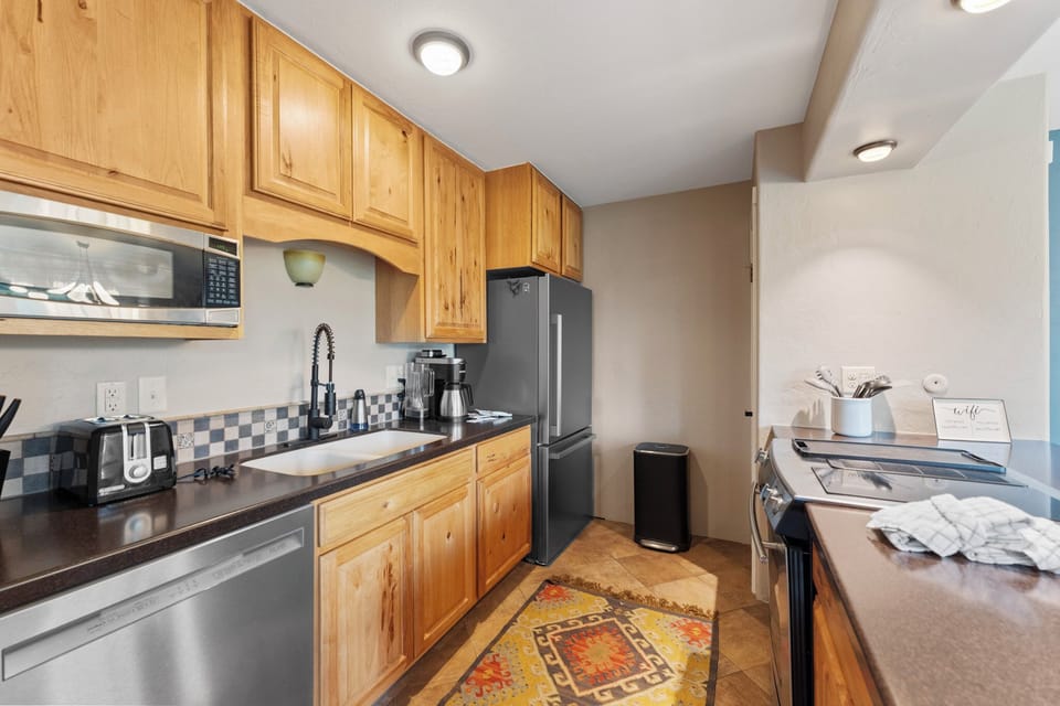 Your fully equipped kitchen features warm wood cabinets, modern stainless appliances, and granite countertops—perfect for preparing memorable meals during your stay.