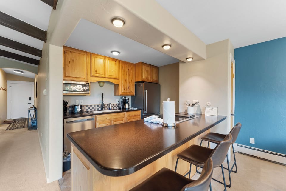 Full kitchen featuring stainless steel appliances and breakfast bar seating 3.