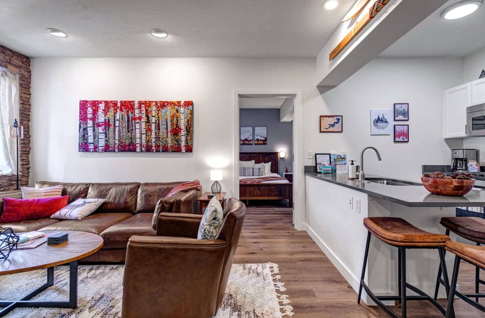 Relax in your cozy living space with rich leather seating, vibrant artwork, and a fully equipped kitchen for all your culinary needs.