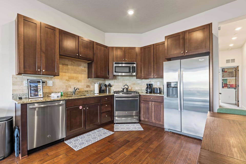 Modern kitchen with rich wood cabinetry, stainless steel appliances, granite countertops, and a warm, inviting atmosphere.