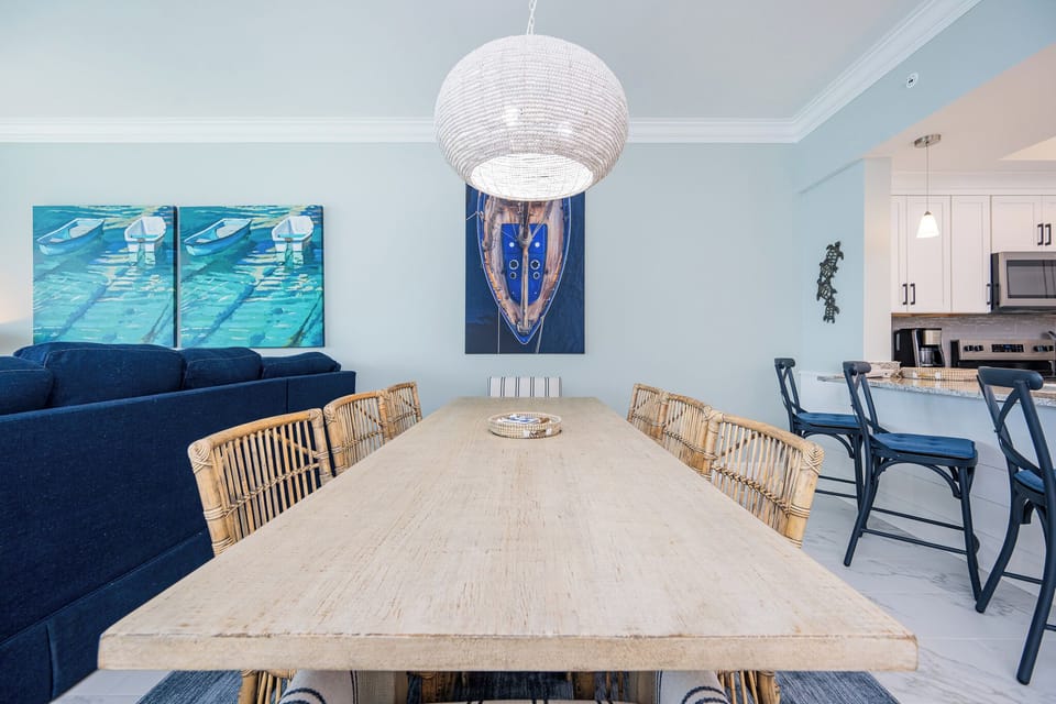 Dine at the rustic wooden table surrounded by stylish seating, with nautical art enhancing the coastal vibe