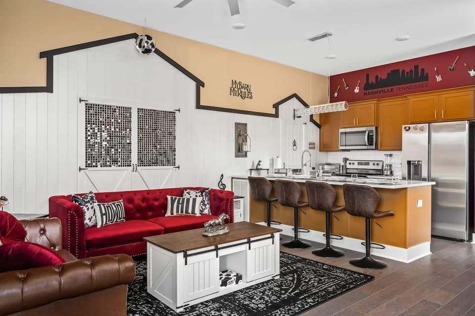 Kick back in this bold Nashville-inspired living space featuring a disco barn wall, plush red sofa, guitar décor, and a fully stocked kitchen with bar seating. Perfect for music lovers and group gatherings with Southern flair!
