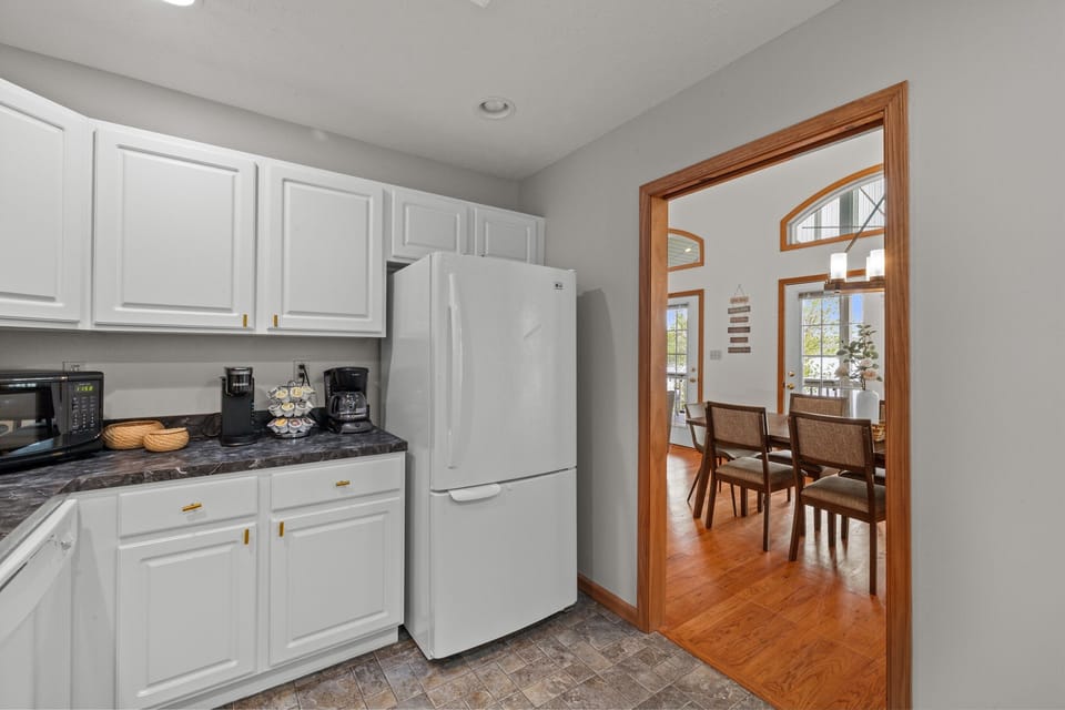 Fully stocked kitchen with white appliances, stainless sink, dishwasher, microwave, toaster, and coffee maker.