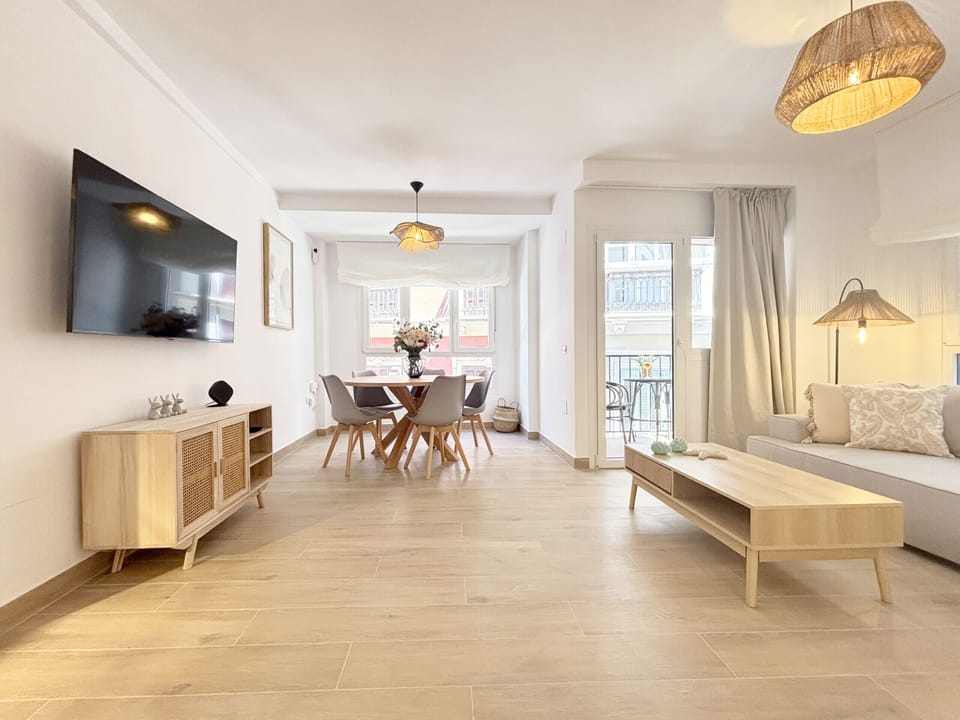 Bright living-dining room featuring a Nordic design aesthetic. This spacious area integrates a comfortable seating zone, a functional dining area, and direct access to an outdoor balcony.