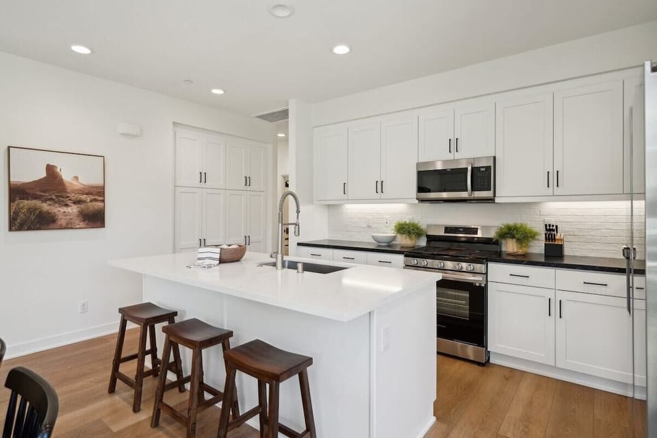 White kitchen with island seating and stainless appliances has everything you need to prepare meals during your stay.