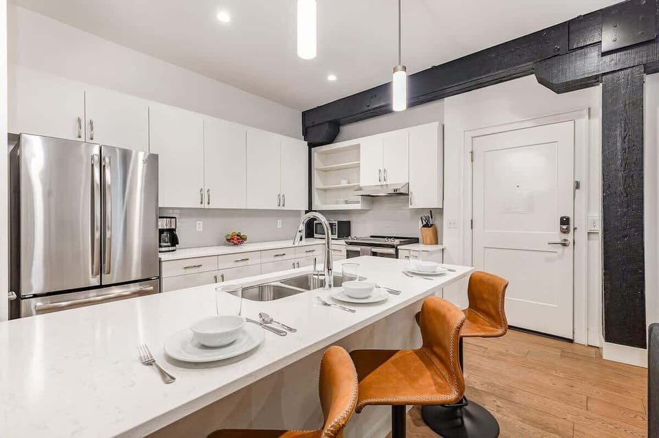 Fully equipped kitchen featuring stainless steel appliances, open counter space, and bar seating for 5 guests.