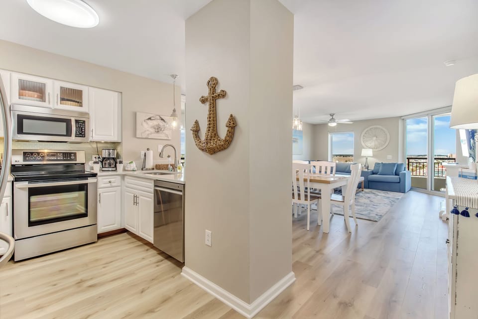 Step into your coastal haven where nautical charm meets modern comfort—fully equipped kitchen flows into bright living space with ocean views.