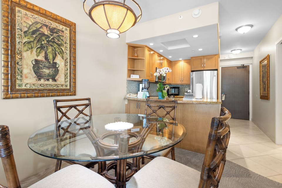 Step into your bright, open-concept space where the kitchen flows seamlessly into your dining area. Sunlight filters through, illuminating the warm wood cabinetry and inviting you to gather around the glass table for meals together.