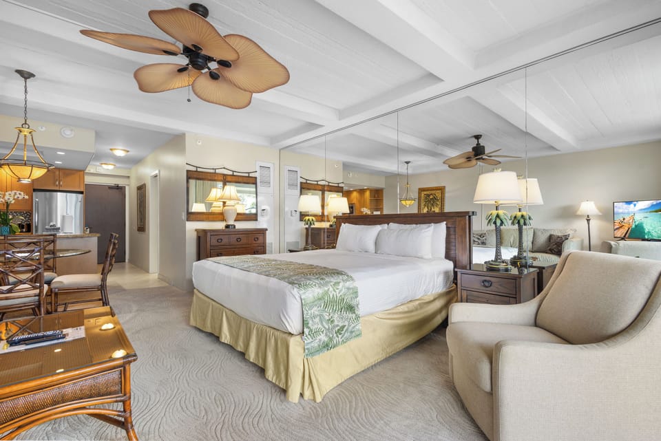 Unwind in your spacious suite with a plush king bed, tropical-inspired decor, and a full kitchen nearby. Ceiling fans and soft lighting create a breezy, relaxing retreat.