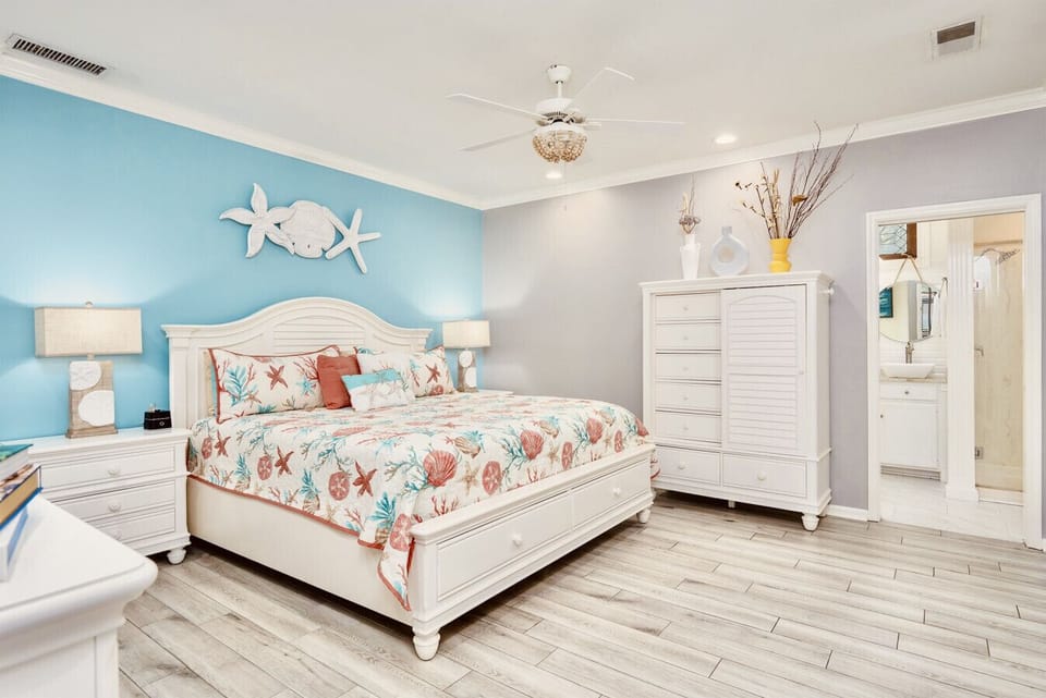 One entire side of the main level contains the spacious primary suite with a king bed with drawers in the footboard. You can store additional clothes in the large 7 drawer door chest with 3 shelves inside the door. The room also has a dresser and TV.