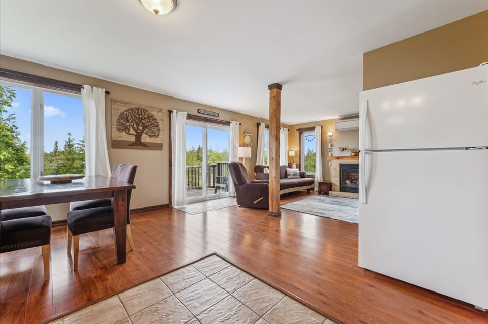 The spacious main floor features a seamless transition from dining to lounging, with a gas fireplace, full-glass patio doors, and warm wood flooring throughout.
