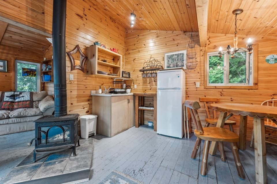 A charming galley-style kitchen is fully equipped for simple cottage meals. Nearby, the wood-burning stove offers both warmth and ambiance for those cooler evenings in the woods.