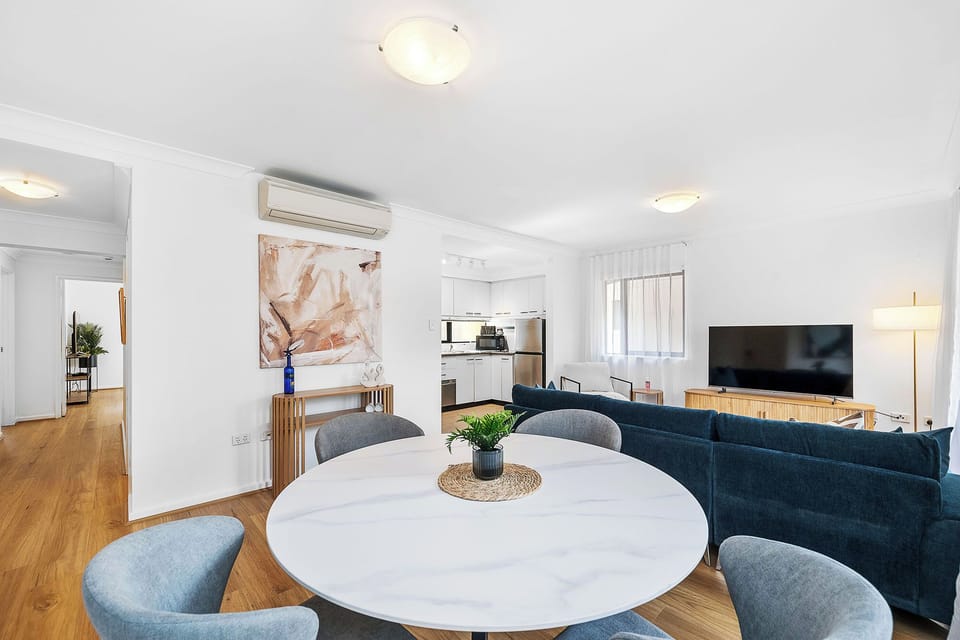 Chic and comfortable open-plan living and dining space with modern decor, air conditioning, and a large TV. Ideal for both relaxation and enjoying meals.