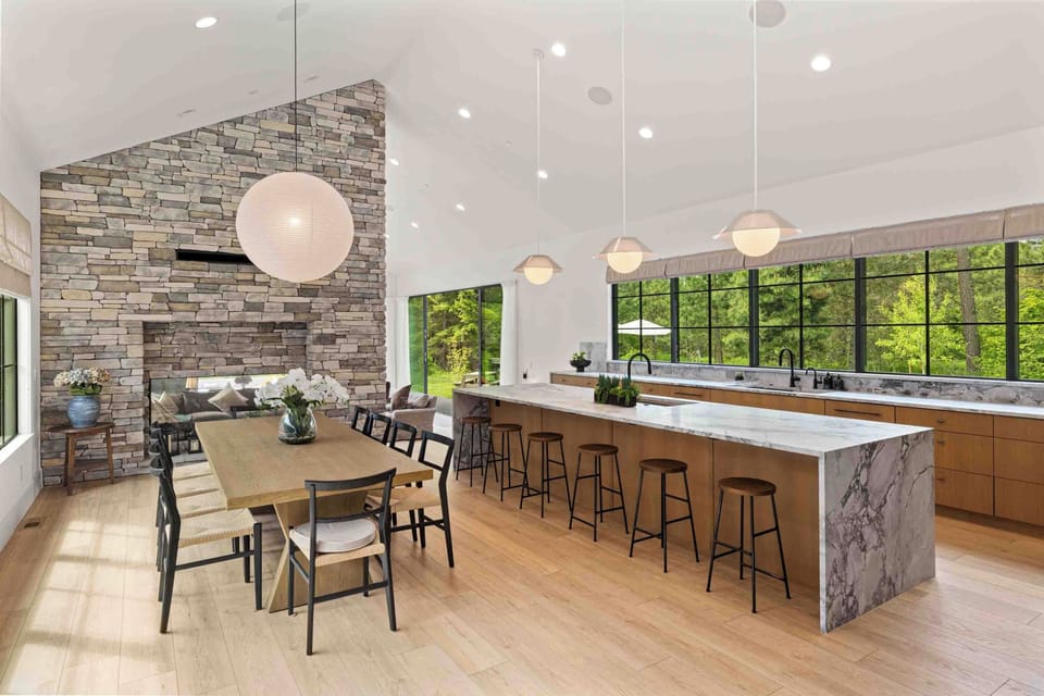 Expansive chef’s kitchen and dining room with waterfall islands, and panoramic nature-facing windows.