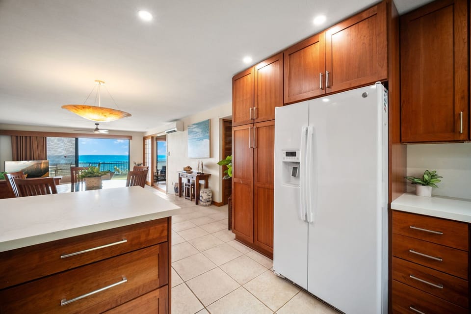 Your fully equipped kitchen opens to a stunning ocean view—picture yourself preparing meals while gazing at turquoise waters and coastal beauty through your private balcony doors.