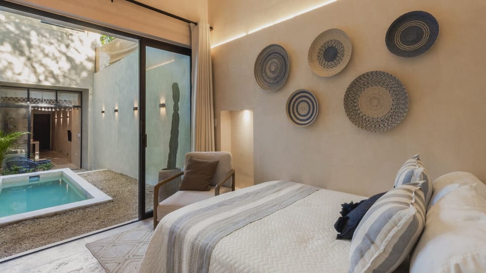 Bedroom: Sunlight dances through large glass doors, leading to a serene private plunge pool