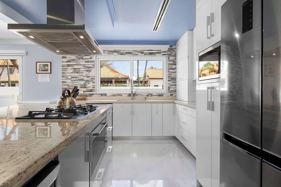 Fully equipped indoor kitchen with stainless steel appliances, island seating for 6, and dining space for 8—ideal for family meals and entertaining.