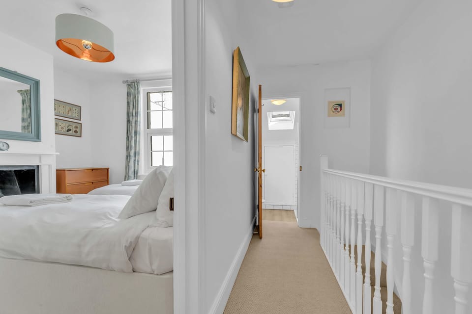 Bright upstairs hallway with white balustrade, soft carpeting, and bedroom and bathroom access
