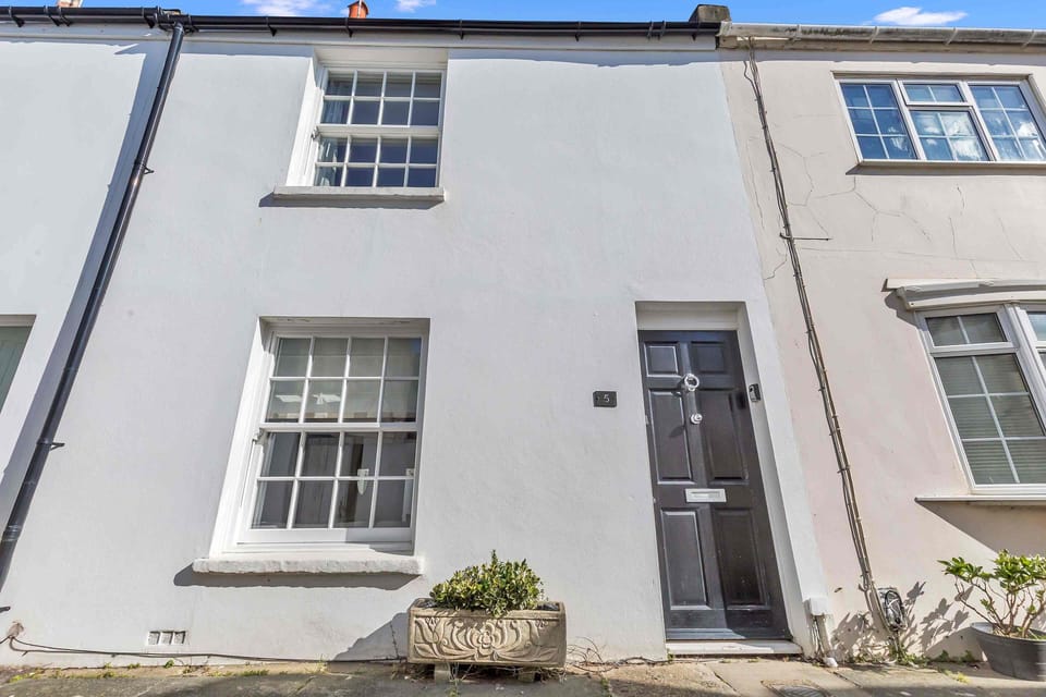 Classic white townhouse facade with a black door in a quiet neighborhood.