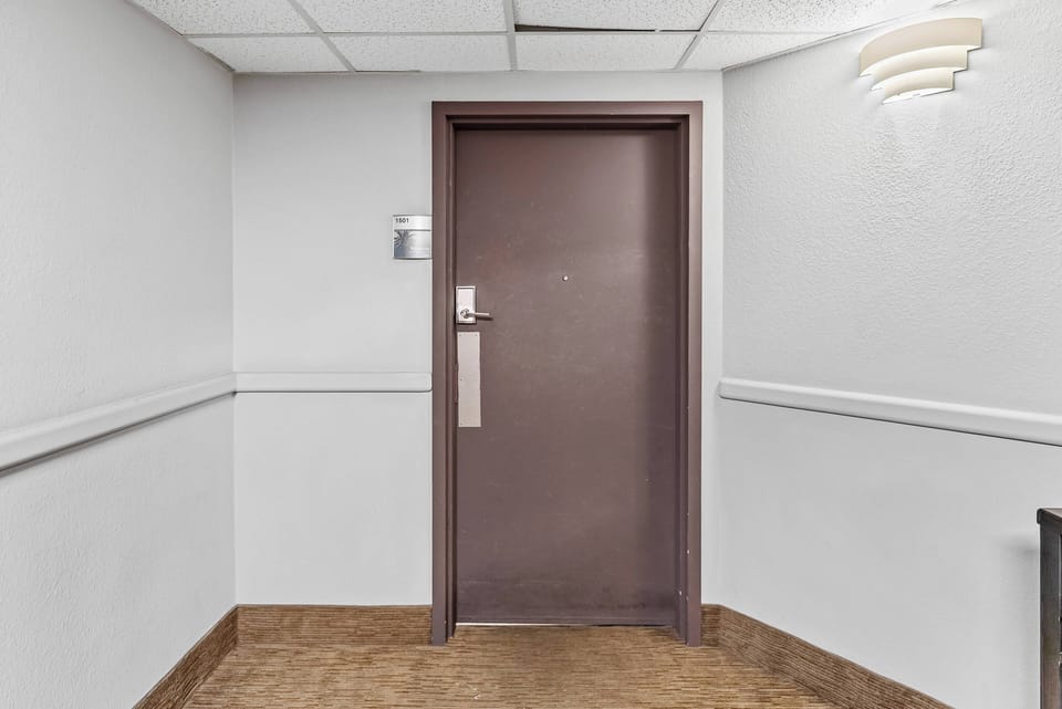 Step into a welcoming corridor that leads to your vacation home, featuring warm brown flooring and soft, ambient lighting. The sturdy door adds a sense of security, inviting you to explore the comfort that awaits behind it.