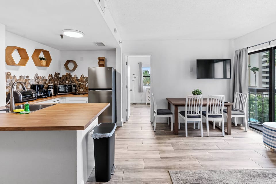 Experience a bright kitchen and dining area with warm wood accents and modern appliances, perfect for culinary adventures. Enjoy shared meals at the inviting table, enhanced by sunlight streaming through the large window.
