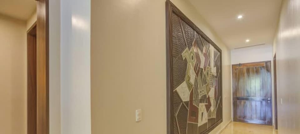 Neutral-toned hallway w/ soft lighting & artwork adding character to the space.